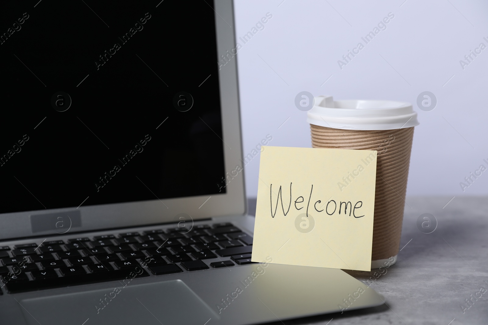 Sticky note with word Welcome, coffee and laptop on grey table, closeup Photo of Sticky note with word Welcome, coffee and laptop on grey table, closeup