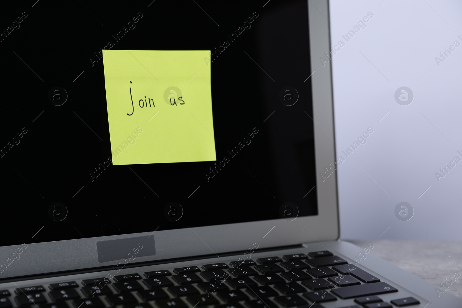 Sticky note with phrase Join Us and laptop on table, closeup Photo of Sticky note with phrase Join Us and laptop on table, closeup