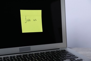 Photo of Sticky note with phrase Join Us and laptop on table, closeup