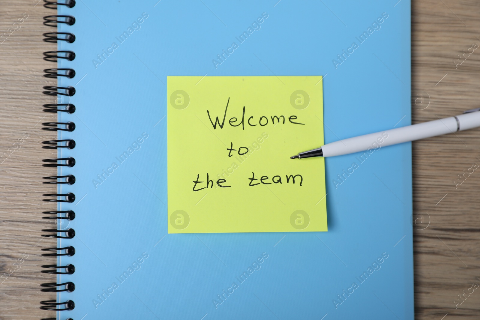 Sticky note with phrase Welcome To The Team, pen and notebook on wooden table, top view Photo of Sticky note with phrase Welcome To The Team, pen and notebook on wooden table, top view
