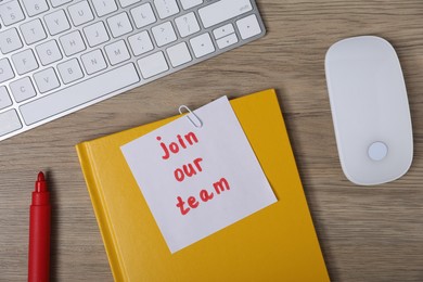 Photo of Sticky note with phrase Join Our Team, marker, notebook, computer keyboard and mouse on wooden table, flat lay