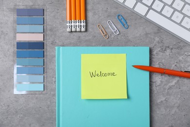 Photo of Sticky note with word Welcome, stationery and keyboard on grey table, flat lay