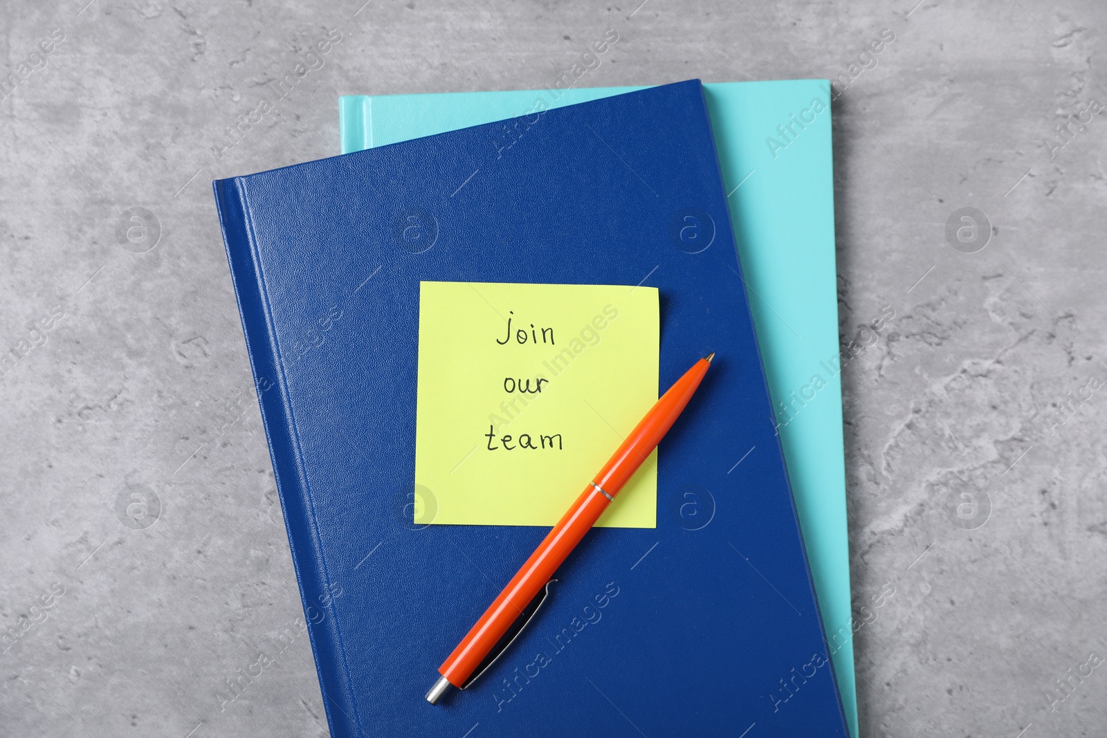 Sticky note with phrase Join Our Team, notebooks and pen on grey table, flat lay Photo of Sticky note with phrase Join Our Team, notebooks and pen on grey table, flat lay