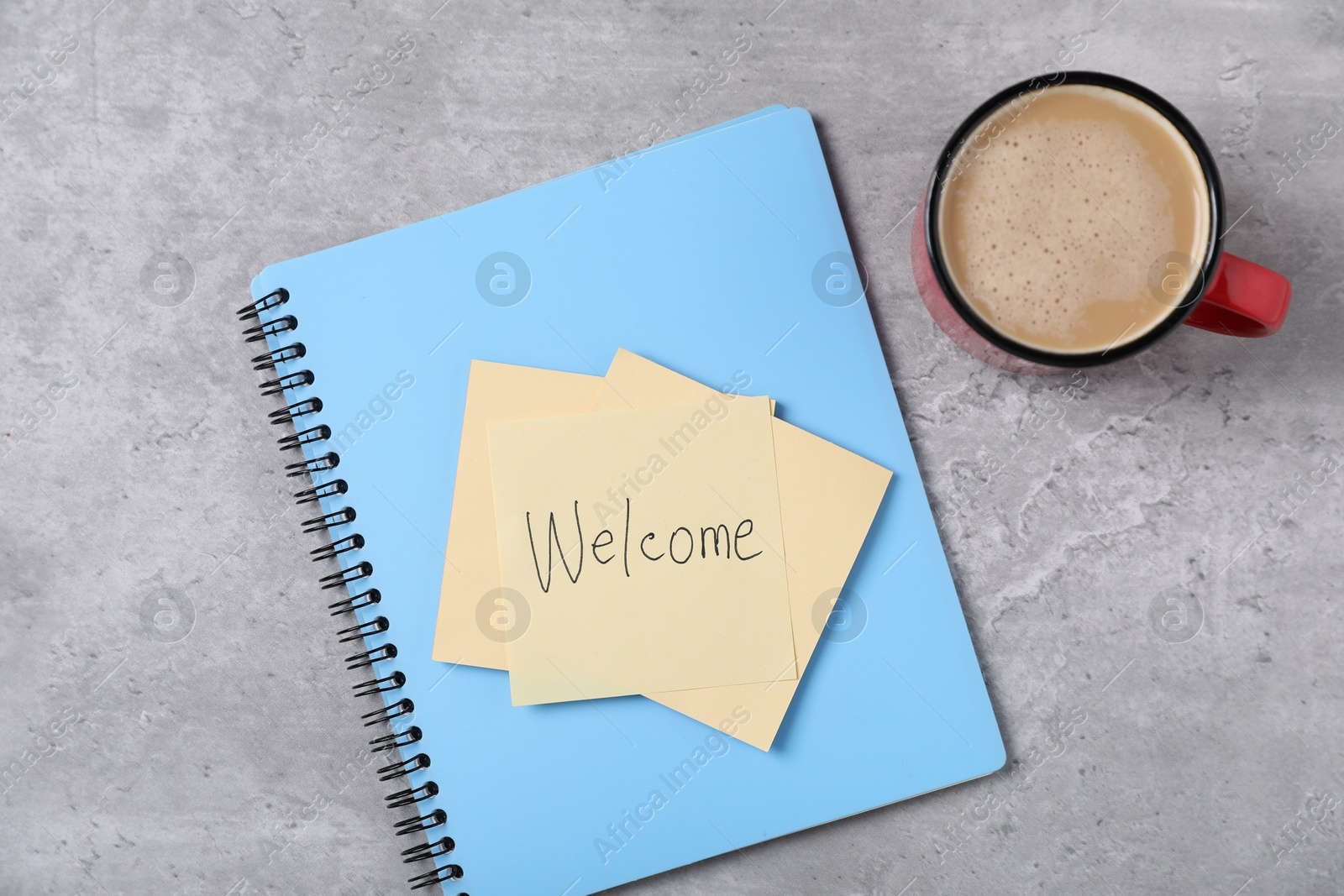 Sticky note with word Welcome, notebook and coffee on grey table, flat lay Photo of Sticky note with word Welcome, notebook and coffee on grey table, flat lay