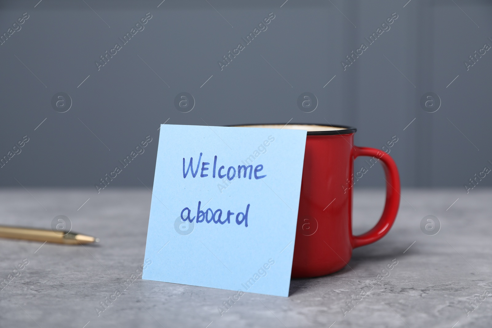 Sticky note with phrase Welcome Aboard, coffee and pen on grey table, closeup Photo of Sticky note with phrase Welcome Aboard, coffee and pen on grey table, closeup