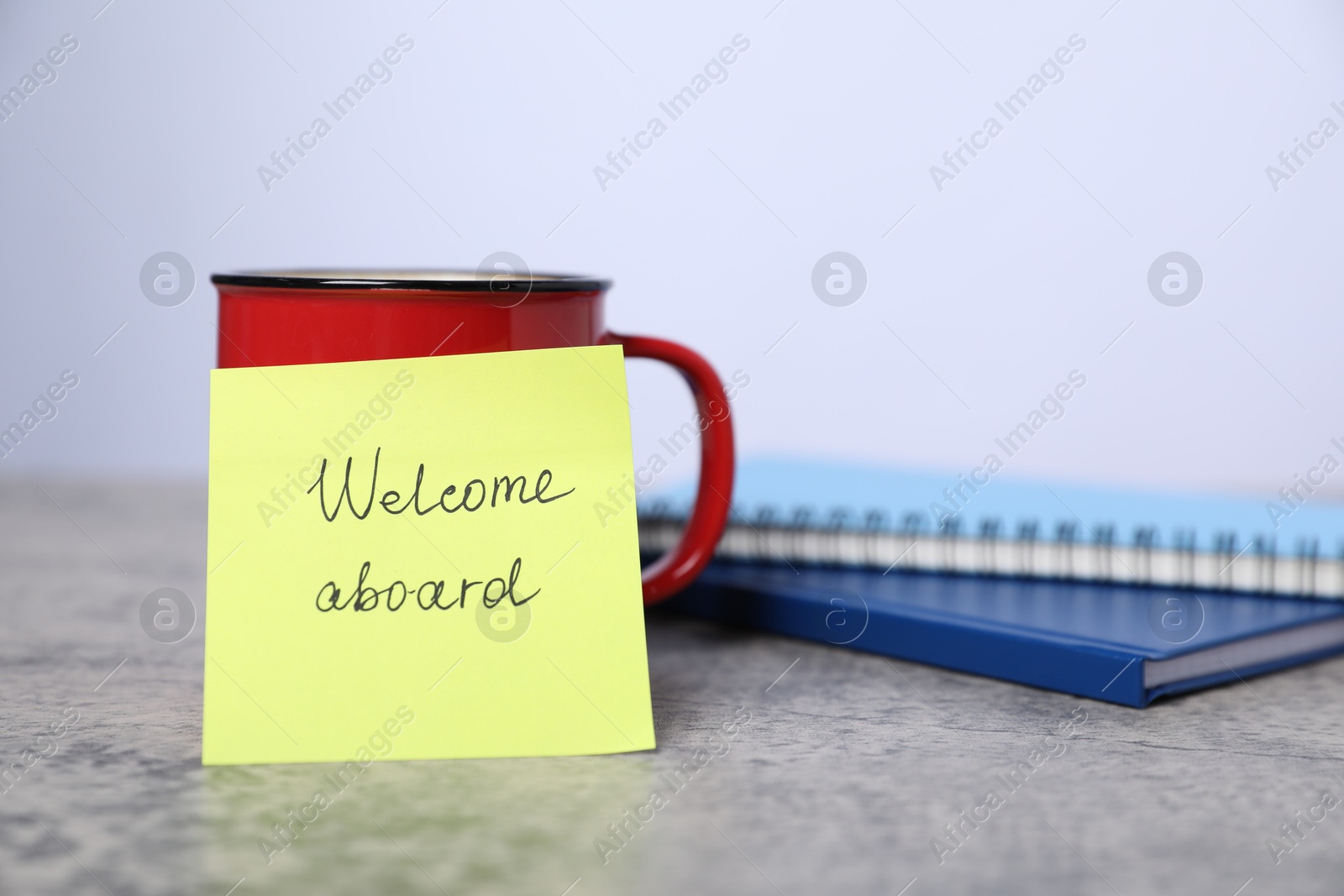 Sticky note with phrase Welcome Aboard, coffee and notebooks on grey table, closeup Photo of Sticky note with phrase Welcome Aboard, coffee and notebooks on grey table, closeup