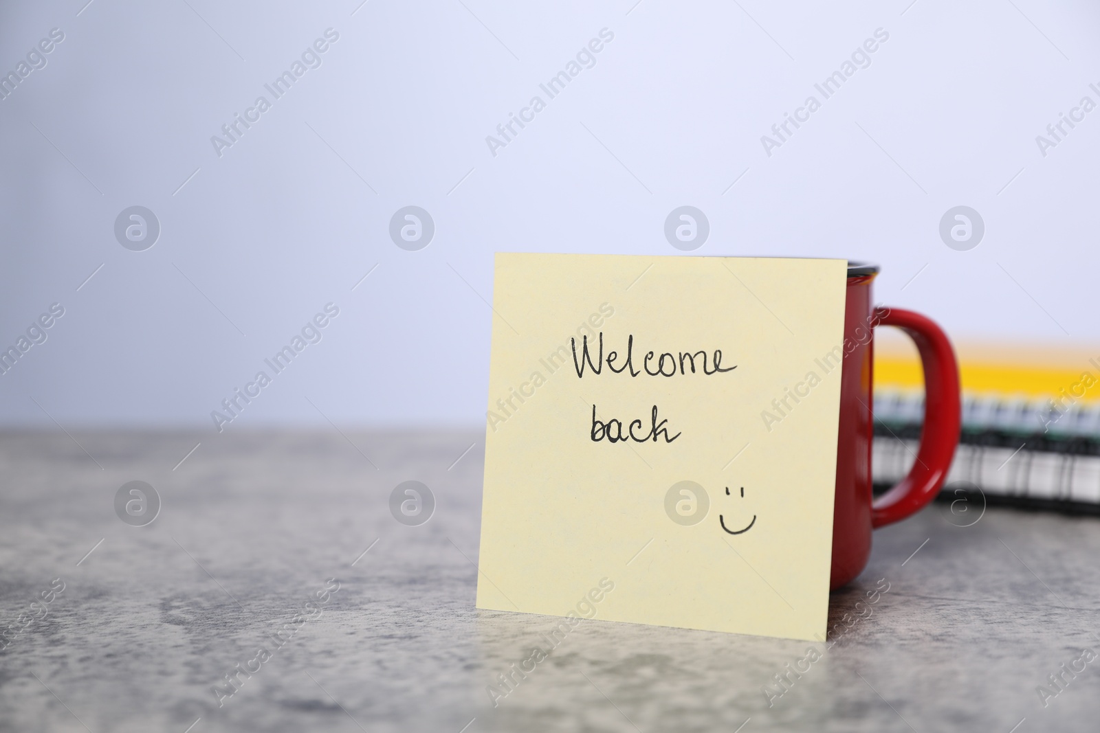 Sticky note with phrase Welcome Back and coffee on grey table, closeup. Space for text Photo of Sticky note with phrase Welcome Back and coffee on grey table, closeup. Space for text