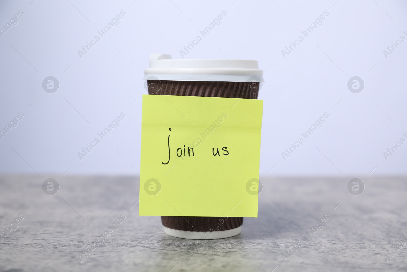 Sticky note with phrase Join Us and coffee on grey table, closeup Photo of Sticky note with phrase Join Us and coffee on grey table, closeup