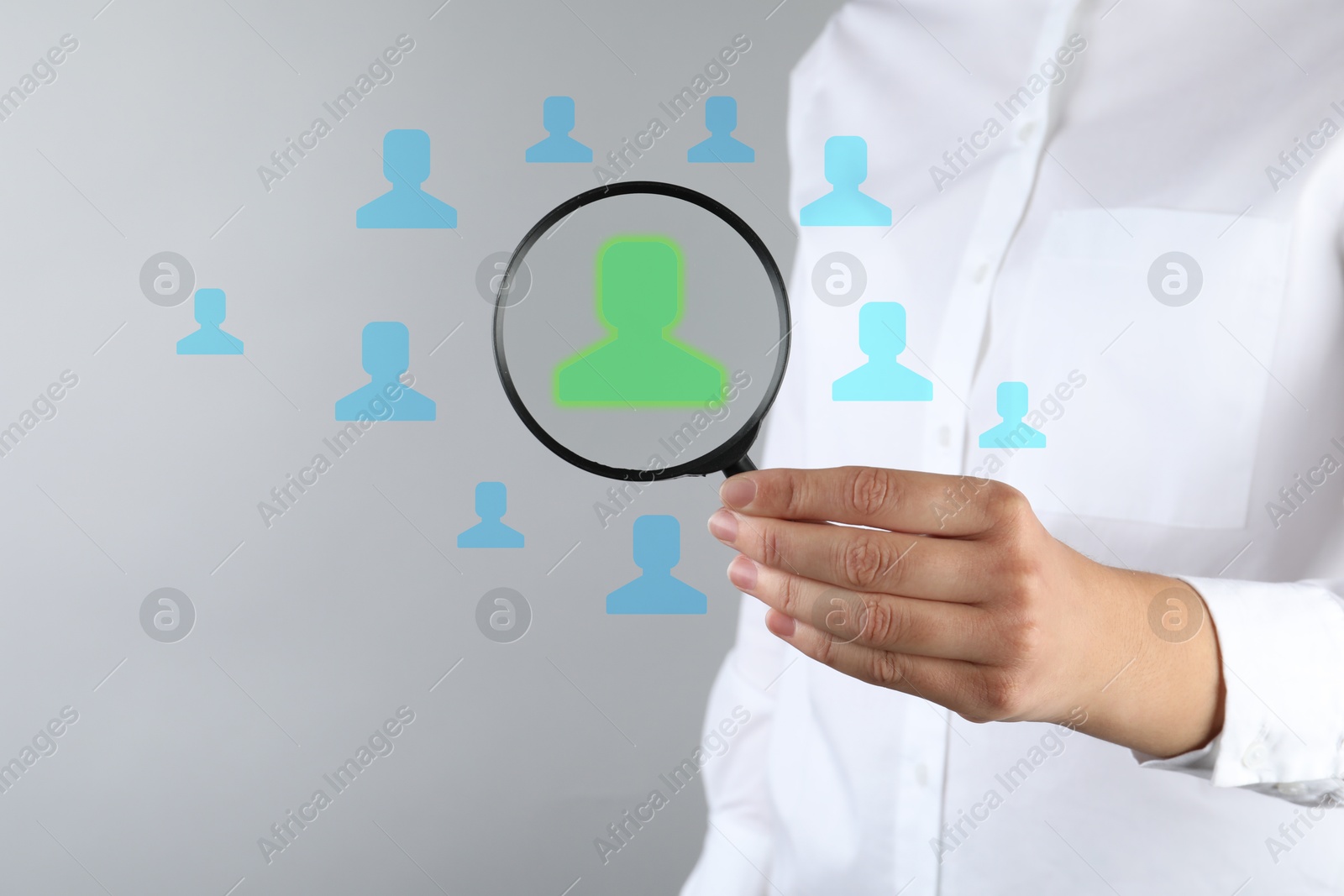 Employee search. HR manager holding magnifying glass over human icons against grey background, closeup Image of Employee search. HR manager holding magnifying glass over human icons against grey background, closeup