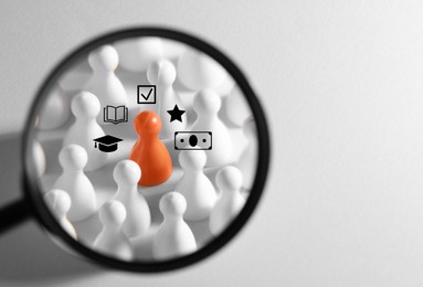 Image of Employee search. Orange pawn among white ones, view through magnifying glass