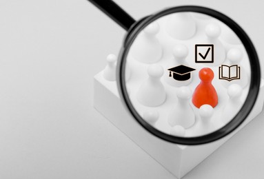Image of Employee search. Orange pawn among white ones, view through magnifying glass