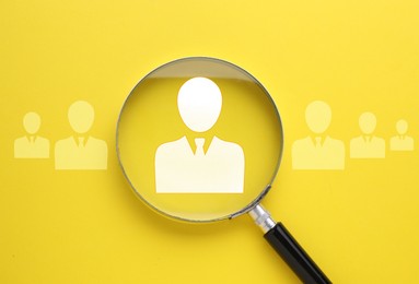 Image of Employee search. Human icons and magnifying glass on yellow background, top view