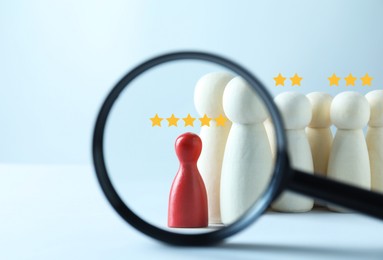 Image of Employee search. Red pawn among white ones, view through magnifying glass