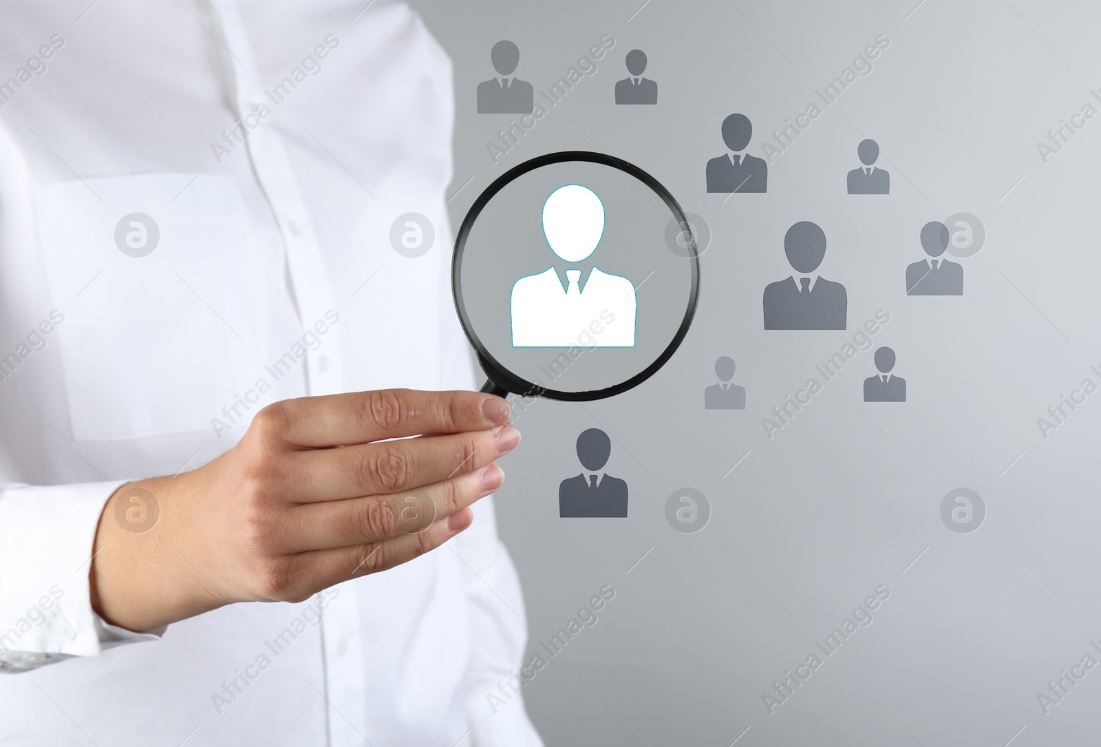 Employee search. HR manager holding magnifying glass over human icons against grey background, closeup Image of Employee search. HR manager holding magnifying glass over human icons against grey background, closeup