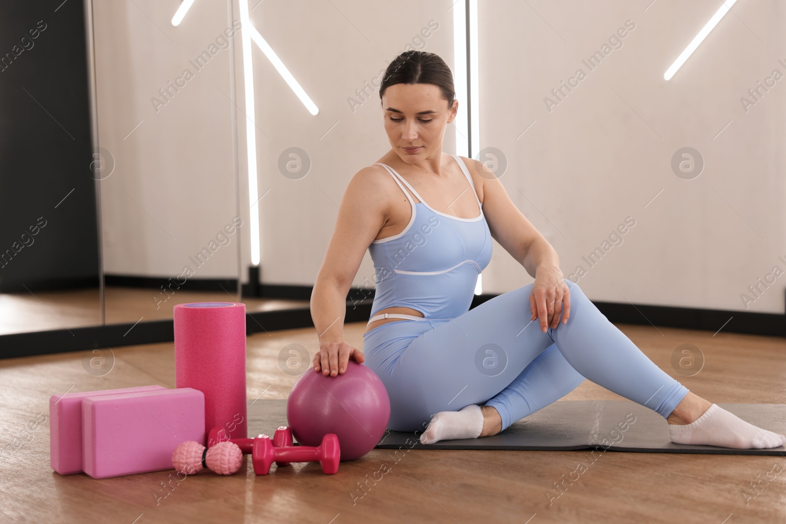 Woman with medicine ball and other sports equipment in fitness studio Photo of Woman with medicine ball and other sports equipment in fitness studio