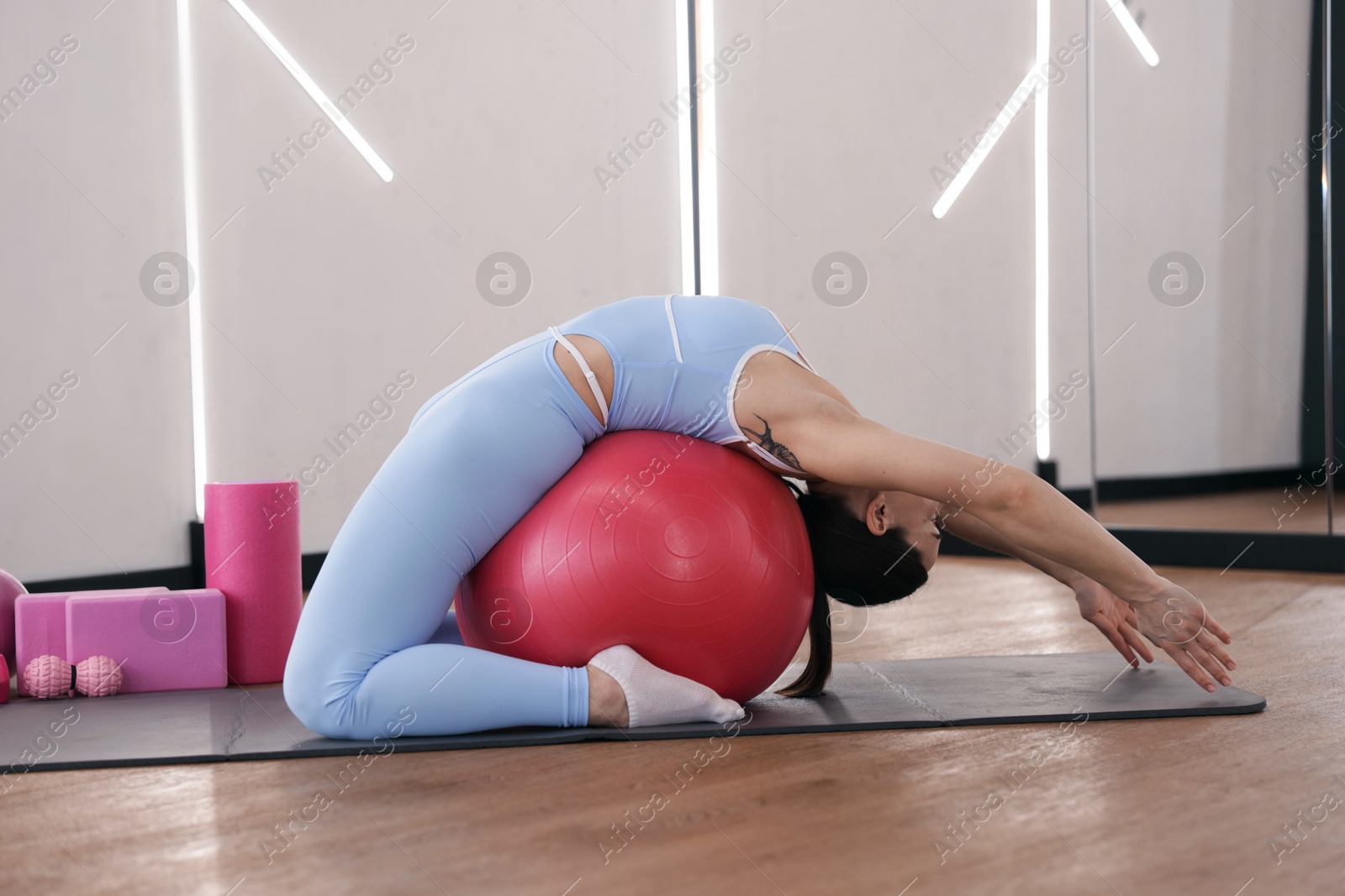Woman exercising with fitness ball on mat in studio Photo of Woman exercising with fitness ball on mat in studio