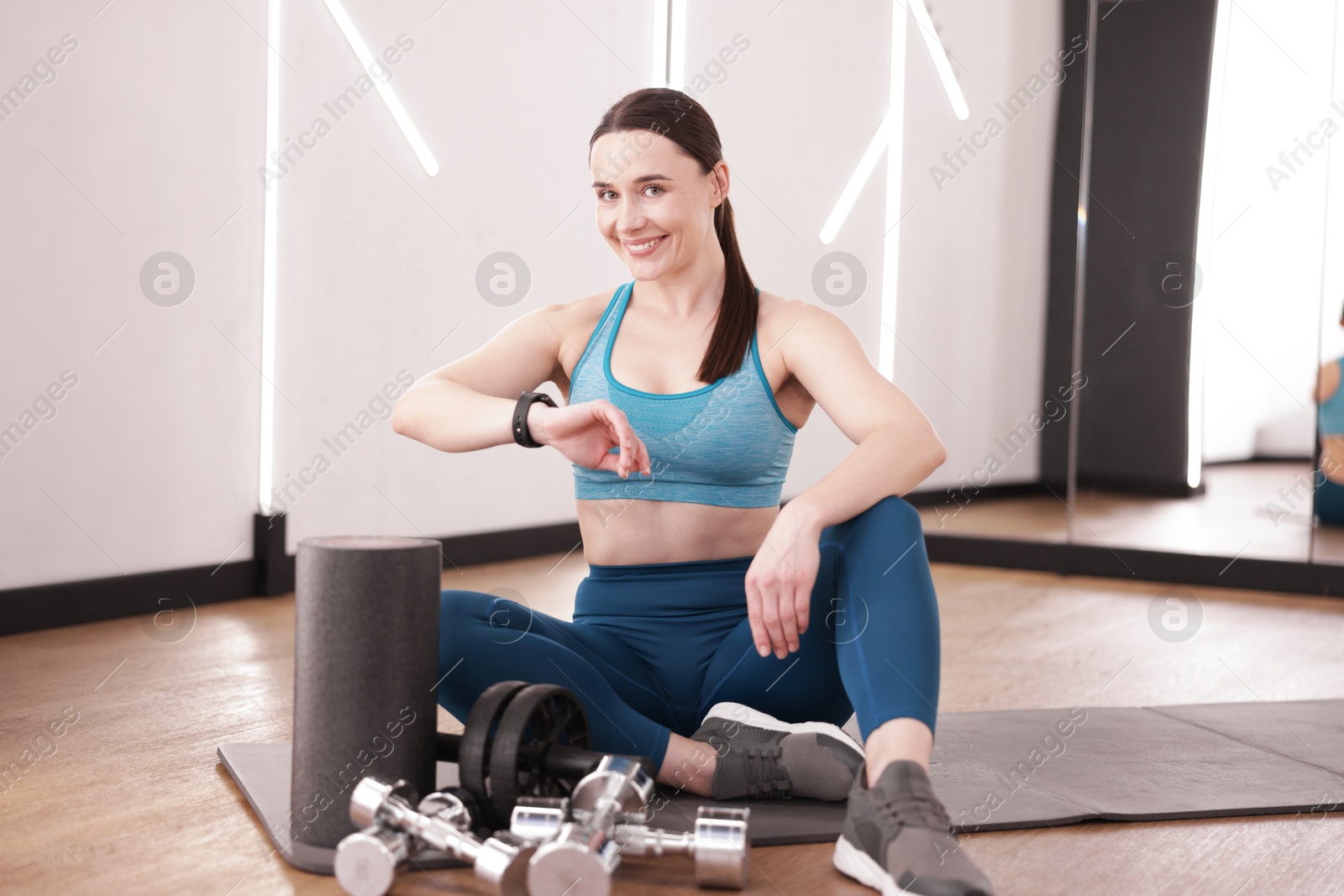 Woman checking fitness tracker during training indoors Photo of Woman checking fitness tracker during training indoors