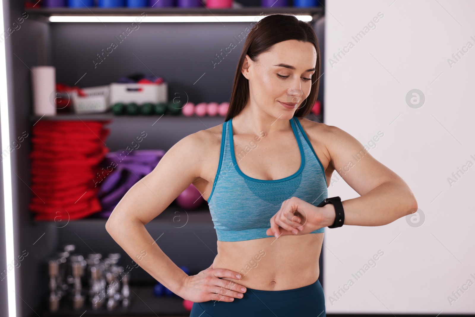 Woman checking fitness tracker during training indoors Photo of Woman checking fitness tracker during training indoors