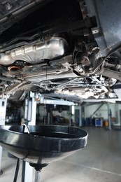 Photo of Dirty old motor oil dripping from car engine into container in workshop, closeup