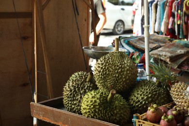 Photo of Fresh ripe durians and other different fruits at market, closeup