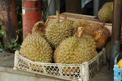 Photo of Fresh ripe durians in crate at market, closeup