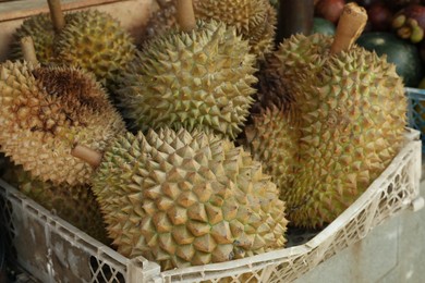 Photo of Fresh ripe durians in crate at market, closeup