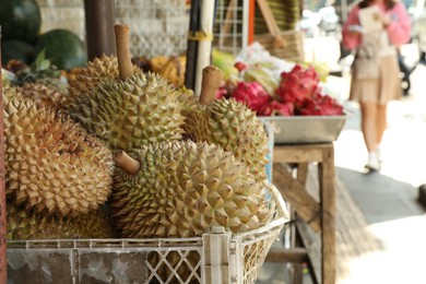 Photo of Fresh ripe durians in crate at market, closeup. Space for text