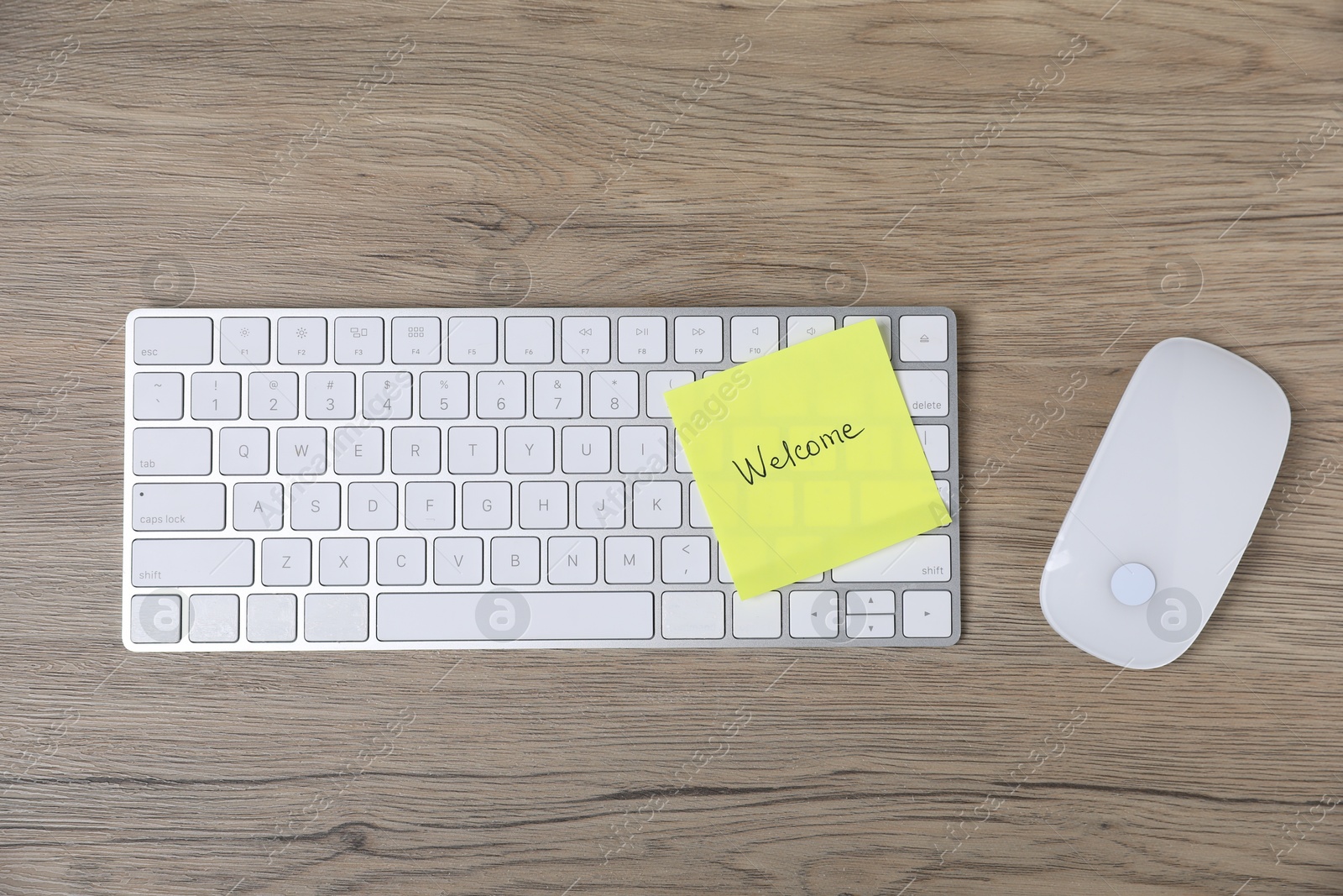 Sticky note with word Welcome, computer keyboard and mouse on wooden table, flat lay Photo of Sticky note with word Welcome, computer keyboard and mouse on wooden table, flat lay