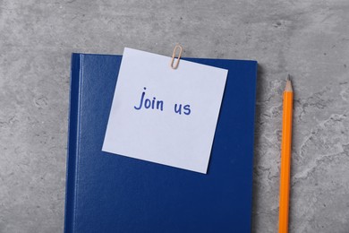 Photo of Sticky note with phrase Join Us, notebook and pencil on grey table, flat lay