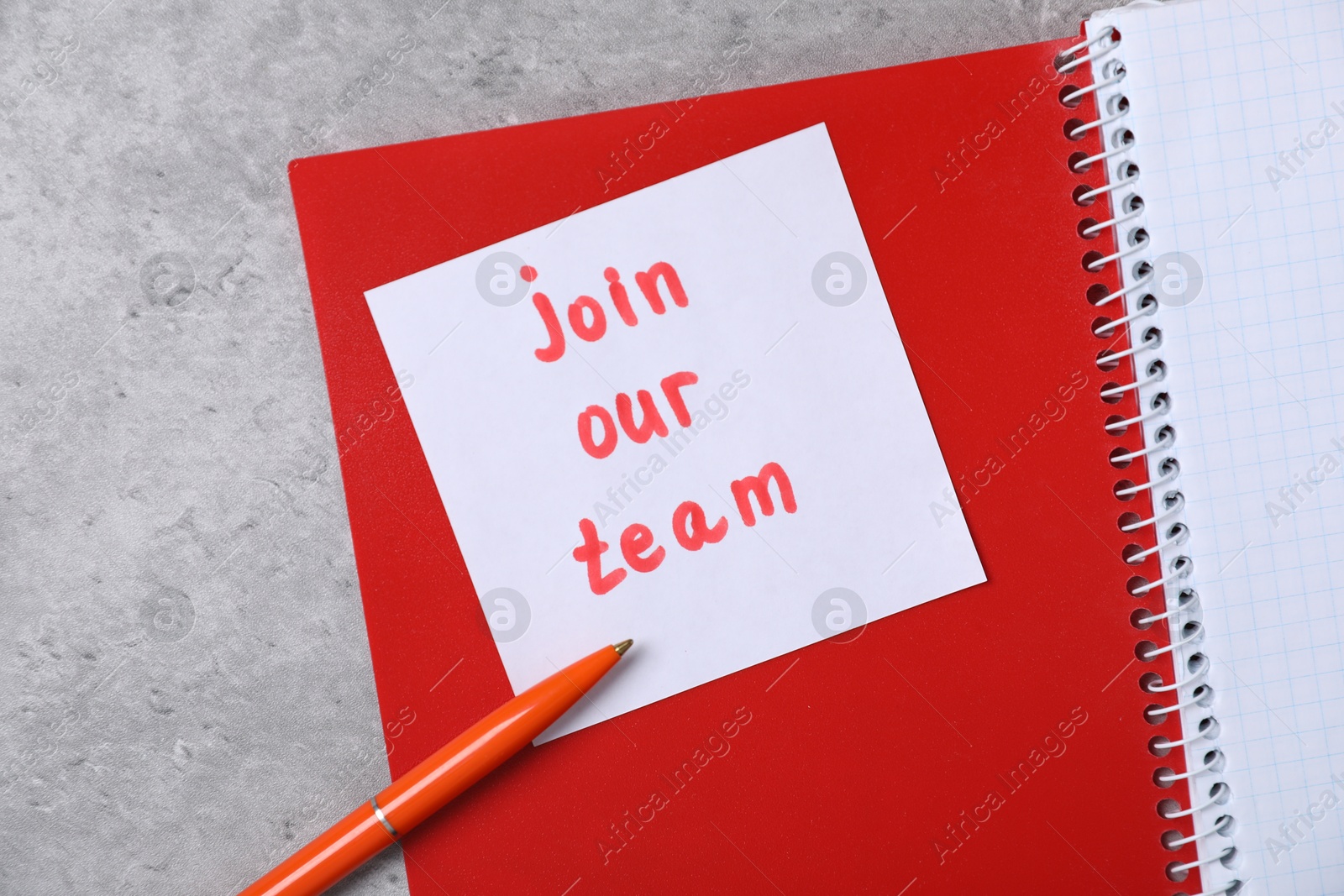 Sticky note with phrase Join Our Team, notebooks and pen on grey table, top view Photo of Sticky note with phrase Join Our Team, notebooks and pen on grey table, top view