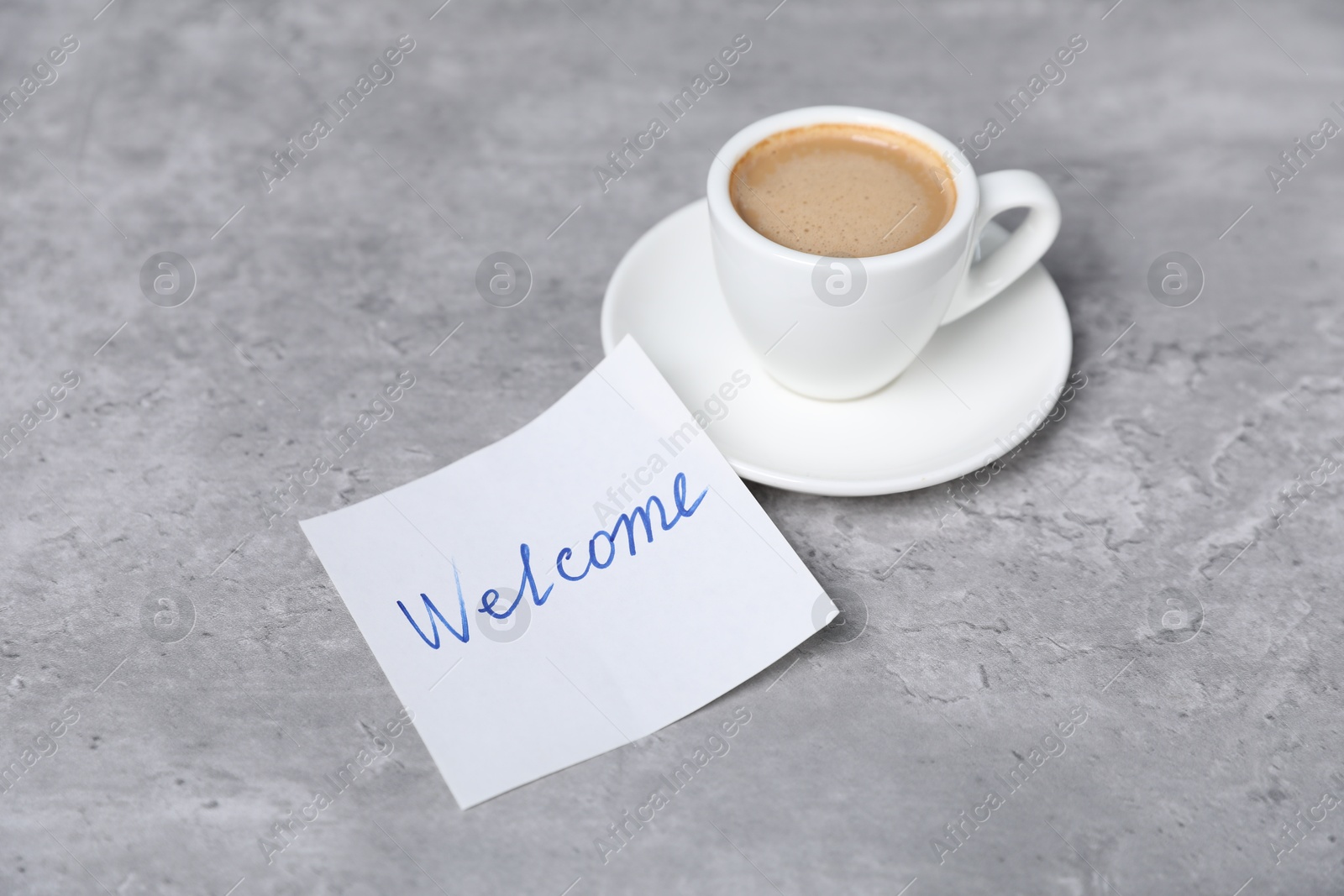 Sticky note with word Welcome and coffee on grey table, closeup Photo of Sticky note with word Welcome and coffee on grey table, closeup