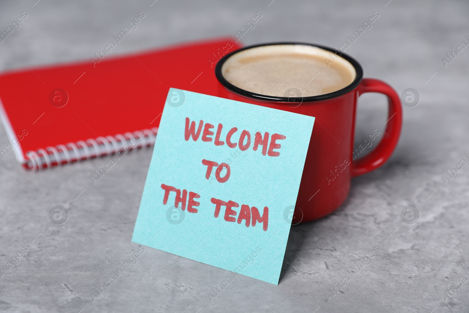 Sticky note with phrase Welcome To The Team, coffee and notebook on grey table, closeup Photo of Sticky note with phrase Welcome To The Team, coffee and notebook on grey table, closeup