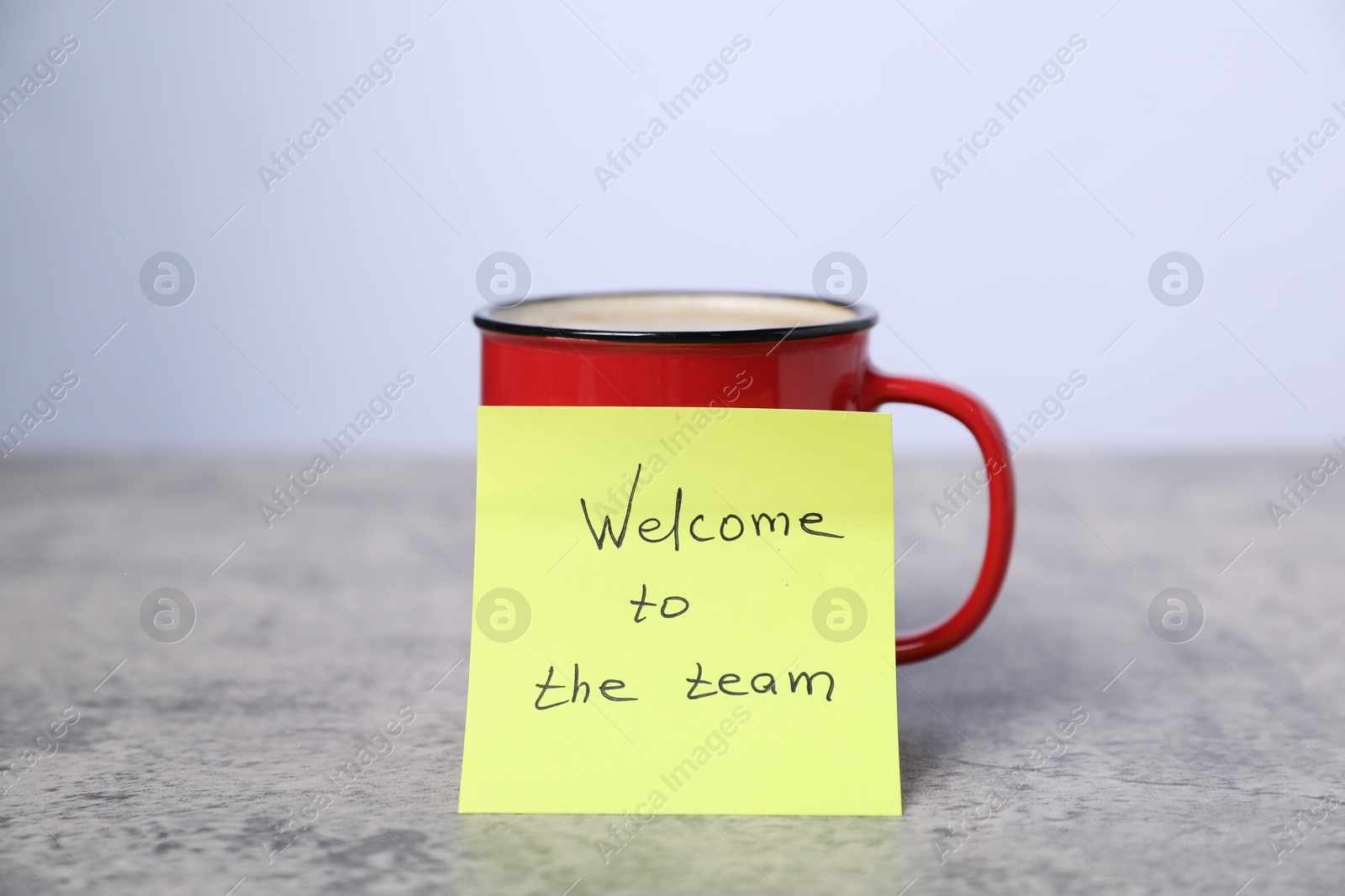 Sticky note with phrase Welcome To The Team and coffee on grey table, closeup Photo of Sticky note with phrase Welcome To The Team and coffee on grey table, closeup