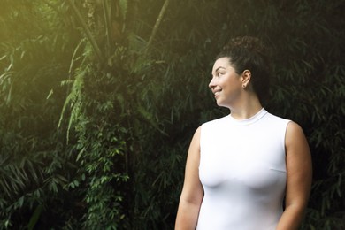Photo of Happy woman in tropical forest, space text copy