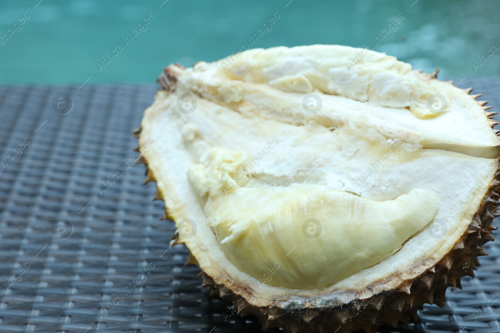 Fresh ripe durian on wicker table near swimming pool outdoors, closeup Photo of Fresh ripe durian on wicker table near swimming pool outdoors, closeup