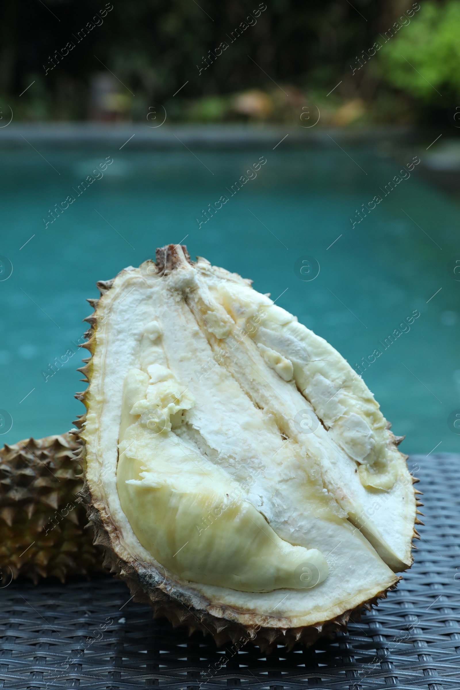 Fresh ripe durian on wicker table near swimming pool outdoors, closeup Photo of Fresh ripe durian on wicker table near swimming pool outdoors, closeup