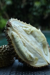Photo of Fresh ripe durian on wicker table near swimming pool outdoors, closeup