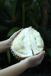 Photo of Woman with fresh ripe durian outdoors, closeup