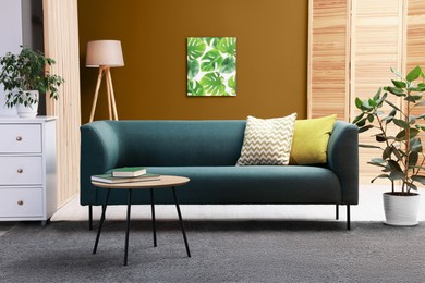 Image of Stylish living room with comfortable teal sofa and color wall. Interior design