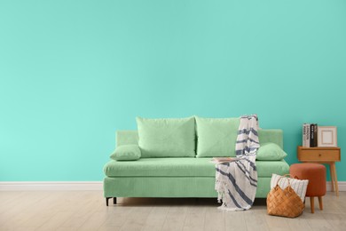 Image of Stylish living room with comfortable sofa and turquoise wall. Interior design