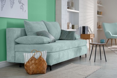 Image of Stylish living room with comfortable mint color sofa and bright wall. Interior design