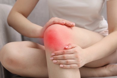 Image of Woman suffering from pain in knee at home, closeup