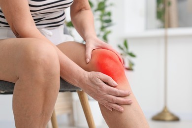 Image of Senior woman suffering from pain in knee at home, closeup