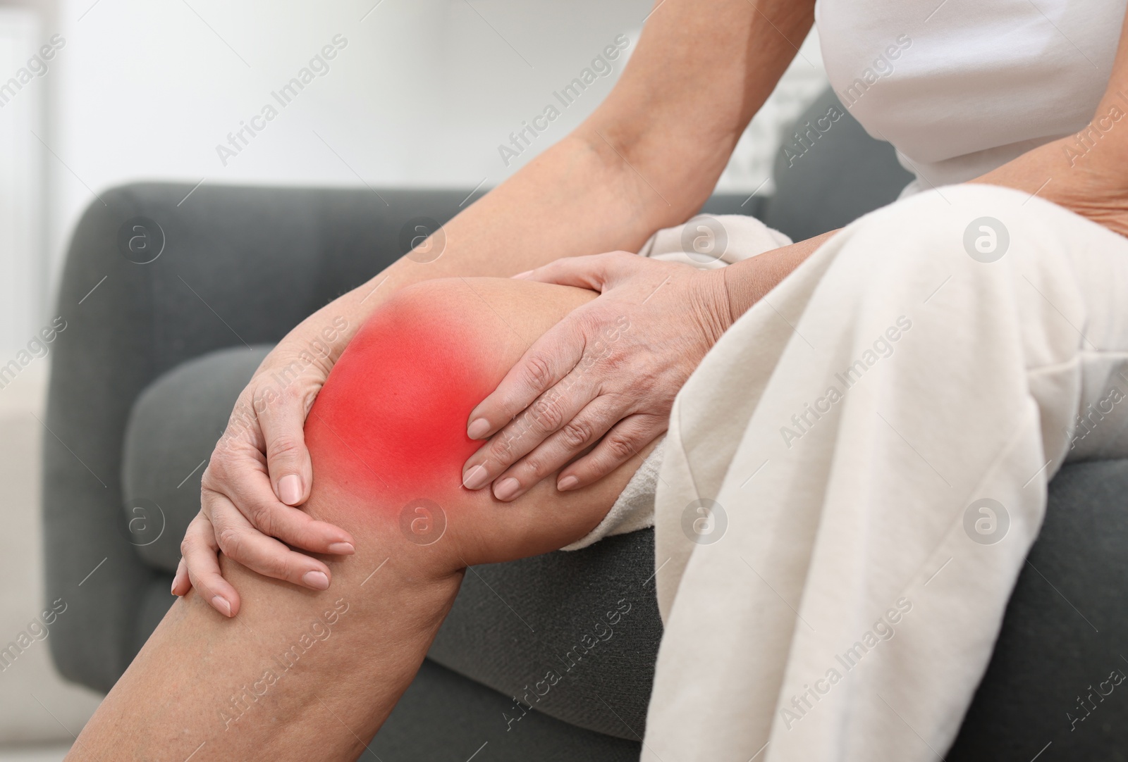 Senior woman suffering from pain in knee on sofa at home, closeup Image of Senior woman suffering from pain in knee on sofa at home, closeup