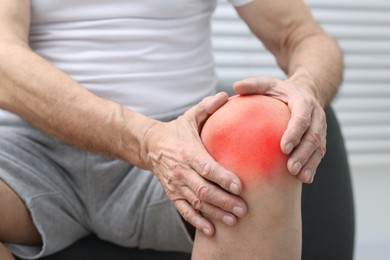 Image of Senior man suffering from pain in knee at home, closeup