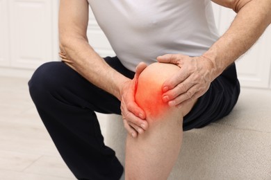 Image of Senior man suffering from pain in knee at home, closeup