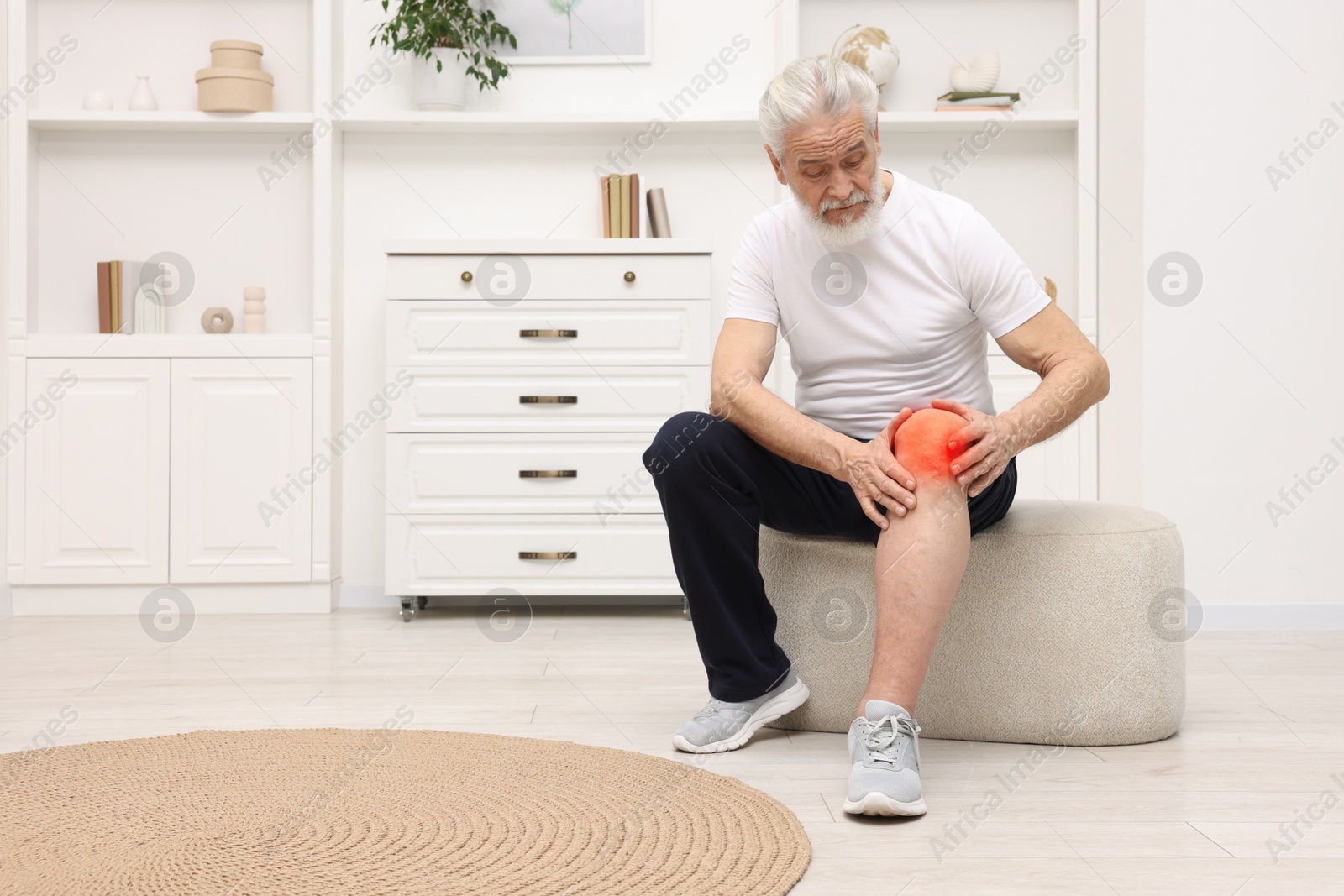 Senior man suffering from pain in knee at home Image of Senior man suffering from pain in knee at home