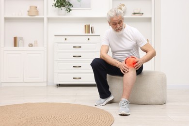 Image of Senior man suffering from pain in knee at home