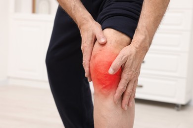 Image of Senior man suffering from pain in knee at home, closeup