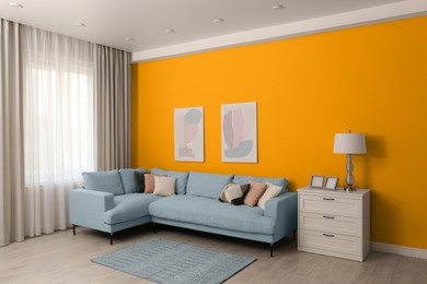 Image of Stylish living room with modern comfortable sofa and orange wall. Interior design